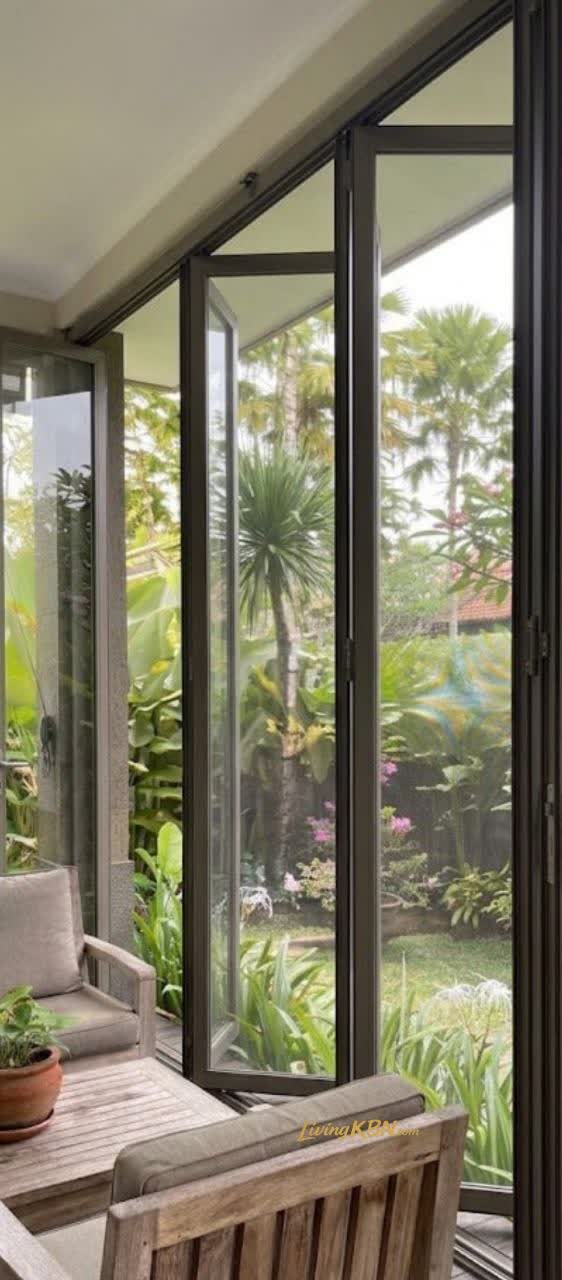 Sliding glass partition frame aluminium hitam pada bukaan lebar menghadap taman